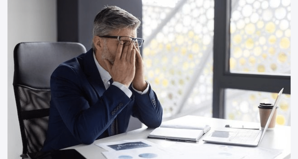 Homme d’affaires stressé au bureau, se tenant le visage après une mauvaise décision d’investissement