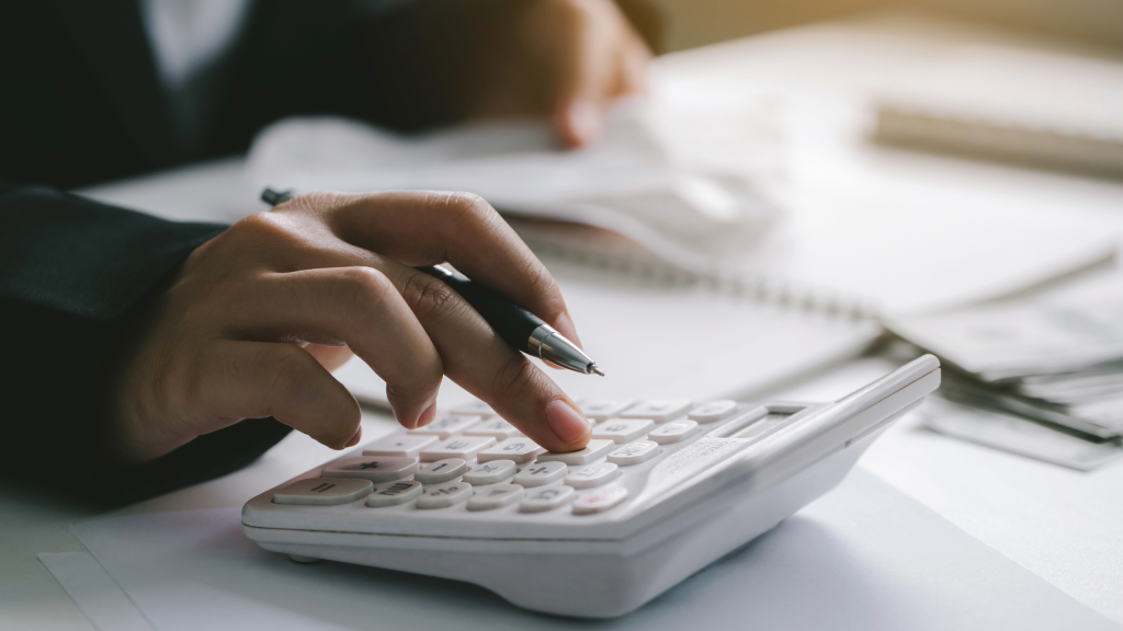 Main d’une personne utilisant une calculatrice pour calculer ses revenus de trading, illustrant le processus de déclaration fiscale