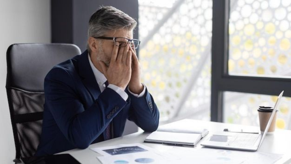 Homme d’affaires stressé devant son ordinateur, illustrant les effets psychologiques du FOMO (Fear of Missing Out) dans le trading et les investissements financiers